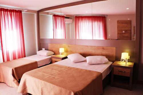 帕塔拉Ferah Hotel的配有红色窗帘的酒店客房的两张床