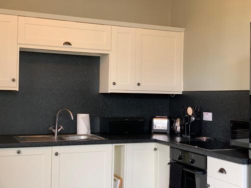 科克茅斯Dovenby Apartment- great base for exploring Lake District的厨房配有白色橱柜和水槽