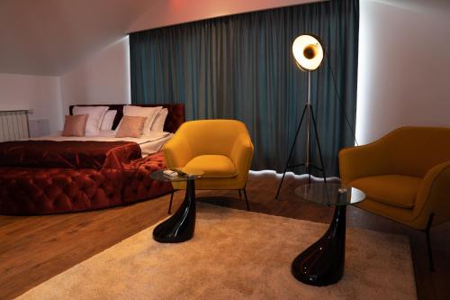 克卢日-纳波卡The Residence Central Jacuzzi Boutique (Adult Only)的一间卧室配有床、两把椅子和一盏灯