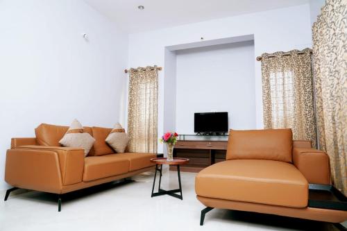迈索尔UNNATHI SUITES的客厅配有2张橙色沙发和电视