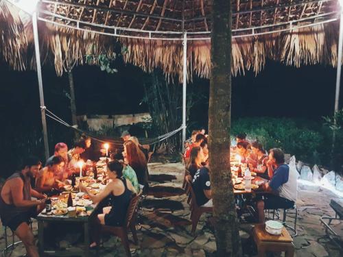 Làng CacDu Gìa - Mường Trà Garden Homestay的一群人坐在桌子上吃着晚上的食物