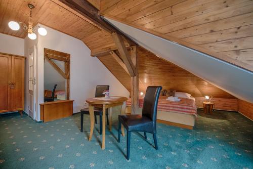 奥斯特拉维采金鹰酒店的一间卧室设有一张床、一张桌子、一张床和一个楼梯。
