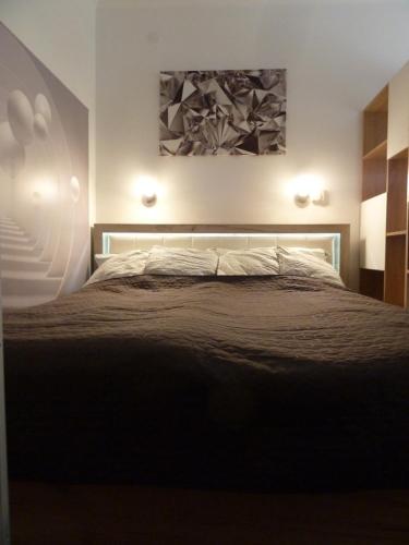 德布勒森ROSE Apartman的卧室配有一张床,墙上挂有绘画作品