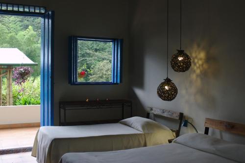 CórdobaSoñarte Reserva Natural的一间卧室设有两张床、窗户和灯光。