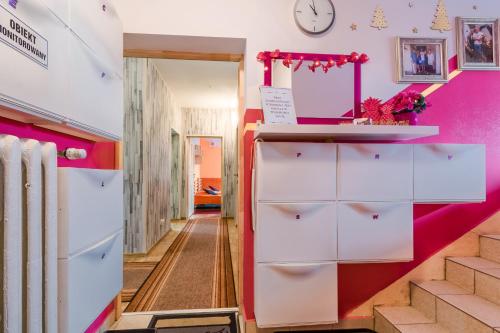 露米雅Pokoje Goscinne Oliwia & Laura I的走廊设有粉色和白色的橱柜和楼梯