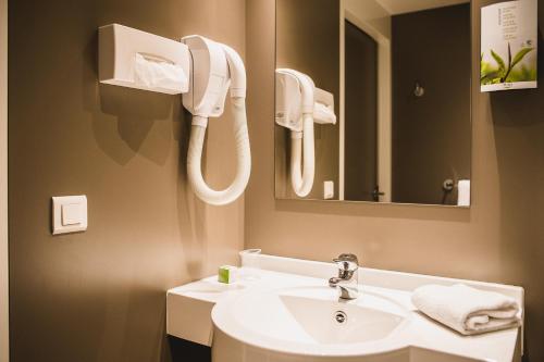 沙勒罗瓦DC Hotel Charleroi Airport的一间带水槽的浴室和墙上的一部电话