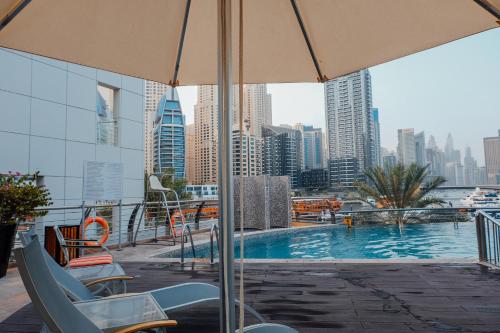 迪拜Spa招牌酒店公寓 的一座大楼顶部的游泳池,配有椅子和遮阳伞