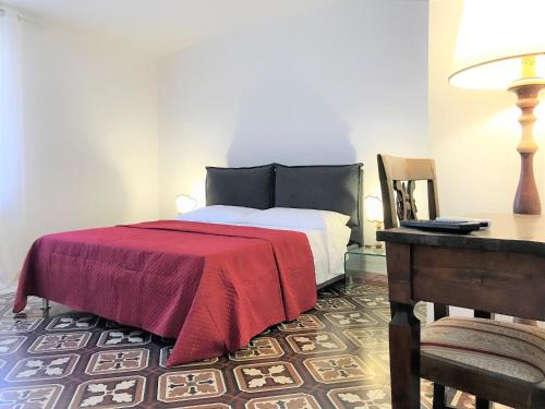 锡耶纳THE BLUE LODGE-cozy flat close to Piazza del Campo的一间卧室配有一张带红色毯子的床和一张书桌