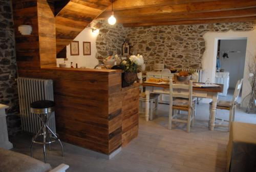 Inverso PinascaChalet in pietra e legno con caminetto的一间厨房和带木墙及桌子的用餐室
