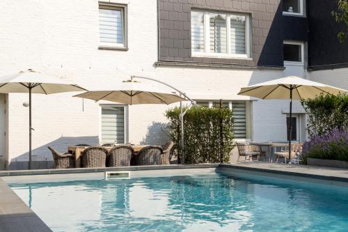 埃本埃迈尔B&B Hostellerie Marie的房屋旁的游泳池配有椅子和遮阳伞