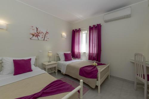 卡武埃鲁罗查拉瓦村度假酒店的一间卧室设有两张床和一个带紫色窗帘的窗户。