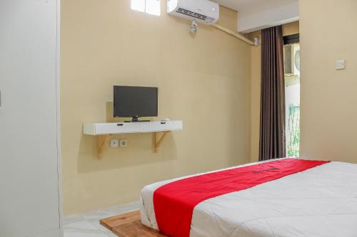 加拉旺RedDoorz Syariah near Pasar Modern Cikopo的一间卧室配有一张床,并在架子上配有电视