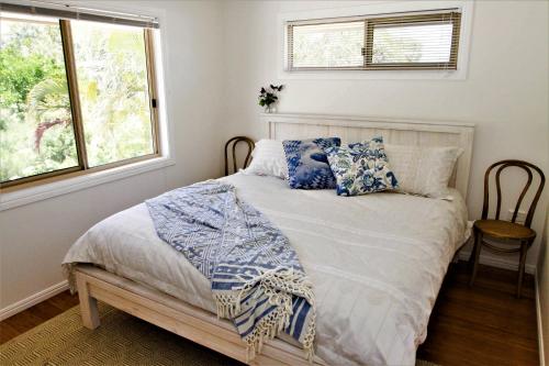 拜伦湾Byron Marvell的一间卧室配有一张带蓝色枕头的床和一扇窗户。