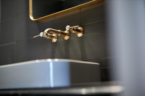 瓦朗斯Hotel Victoria的浴室水槽设有水龙头和镜子