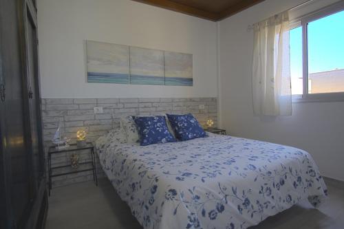 格拉纳迪利亚德亚沃纳ÁTICO LAS ALGAS的一间卧室配有一张带蓝色和白色床单的床和窗户。