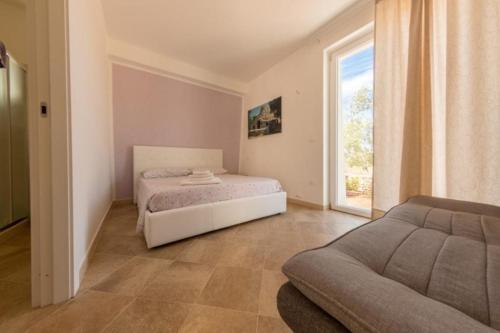佩斯科勒海滨Tenuta Ciullo的一间卧室配有一张床、一张沙发和一个窗口