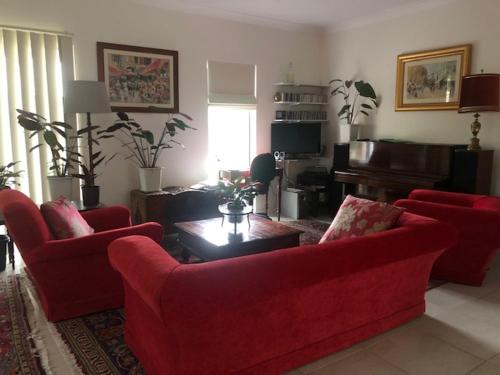 West RichmondNot quite the Ritz的客厅配有2张红色沙发和1台钢琴