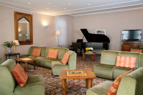 Premeno摩德诺酒店的客厅配有绿色沙发和钢琴
