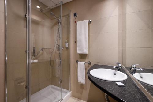 阿威罗阿维罗宫酒店的一间带玻璃淋浴和水槽的浴室