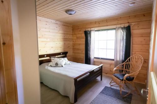 兰塔萨尔米Villa Vahtivuori的一间卧室设有一张床、一个窗口和一把椅子