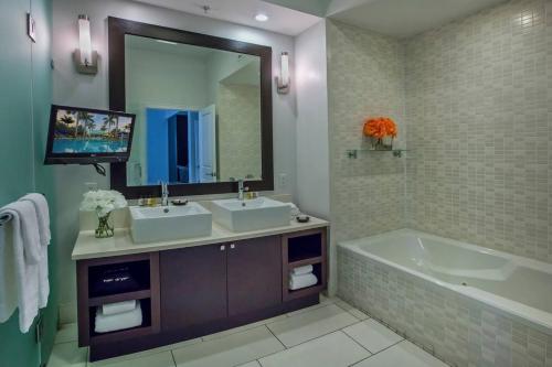 迈阿密普罗威登多拉布鲁酒店的一间带两个盥洗盆和浴缸的浴室以及一台电视。