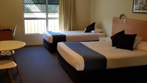 楠伯南博高地汽车旅馆的酒店客房设有两张床和一张桌子。