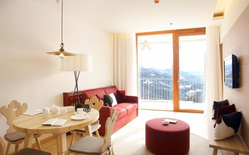 卡奇山口Falkensteiner Residences edelweiss的客厅配有桌子和红色沙发