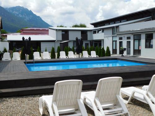 泽尔内什蒂Mountain Vista Suites的一组白色椅子和一个游泳池
