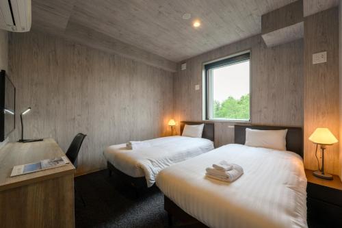 二世古Midtown Niseko的酒店客房设有两张床和窗户。