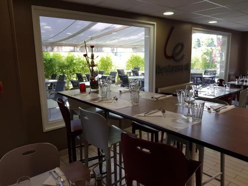 布拉尼亚克钟楼图卢兹布拉纳克机场酒店的餐厅设有桌椅和大窗户。
