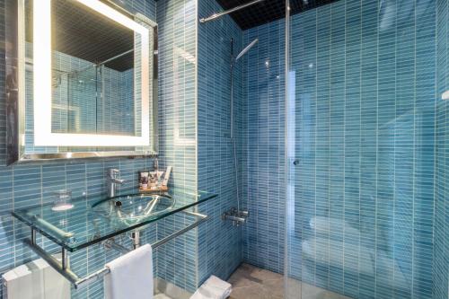 阿尔赫西拉斯阿尔赫西拉斯美居酒店的蓝色瓷砖浴室设有水槽和镜子