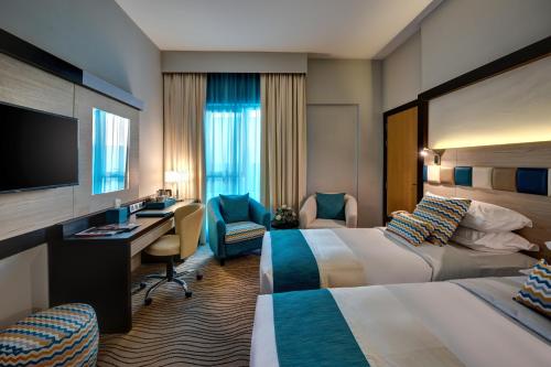 迪拜City Avenue Hotel的酒店客房配有两张床和一张书桌