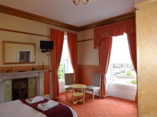 邓弗里斯邓弗里斯维拉旅馆的一间卧室配有一张床、一张桌子和一个壁炉