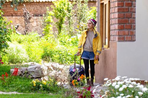 乌鲁班巴Allin Illary Eco Hospedaje的站在花园的女人,带着手提箱