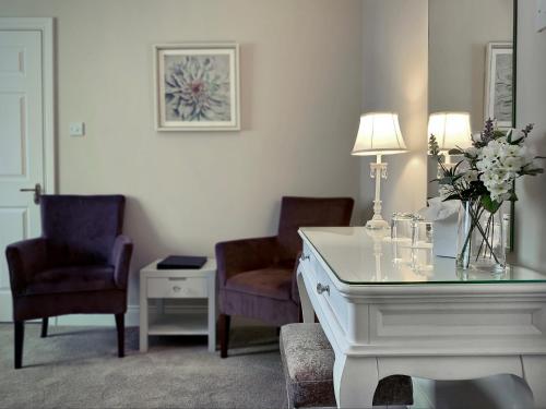 基拉尼翠鸟旅馆的一间房间,配有两把椅子和一张鲜花桌子
