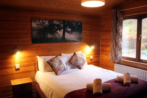 格伦科Rowan Tree Lodge的木制客房内的一间卧室,配有一张床
