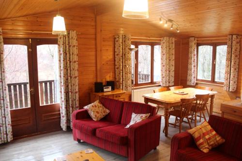 格伦科Rowan Tree Lodge的客厅配有红色的沙发和桌子