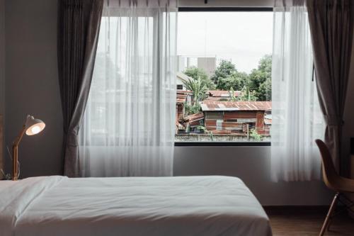 乌隆他尼Clay Hotel Udonthani的一间卧室设有一张床和一个大窗户