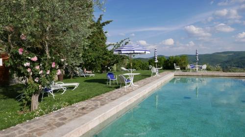 潘札诺勒巴罗别墅酒店的一个带椅子和桌子的游泳池以及一把遮阳伞