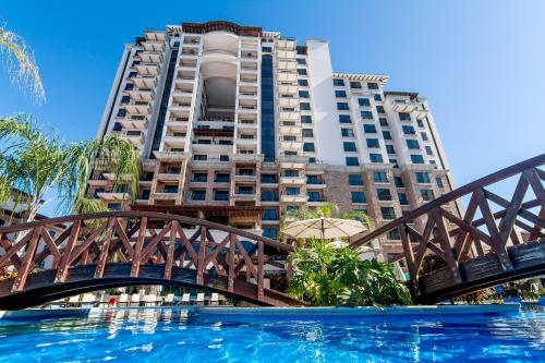 雅科Crocs Resort & Casino的一座高楼前的一座游泳池上的桥梁