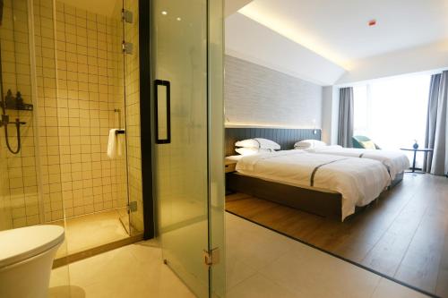 杭州Hangzhou Yuqi Hotel - West Lake Leifeng Tower Branch的一间卧室配有一张床,浴室设有淋浴。