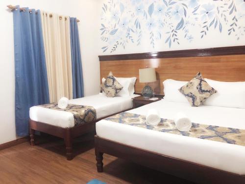 科隆Blue Waters Inn Coron Palawan的一间卧室配有两张床和一张桌子,两把椅子