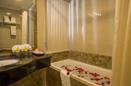 胡志明市Huong Sen Hotel的浴室配有浴缸和花卉盥洗池,位于地板上
