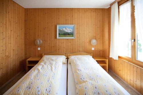 翁根雪绒花酒店的木墙客房的两张床