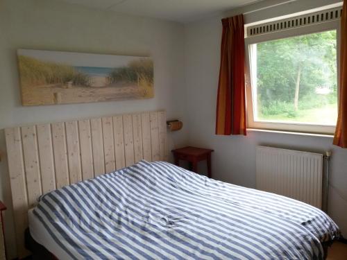 海牙Kijkduinvilla的一间卧室配有一张带条纹床罩的床和窗户