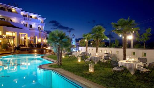 特里卡拉Aeton Melathron Hotel的拥有游泳池、桌子和棕榈树的酒店