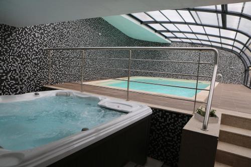 奥利维拉多霍斯比托Hotel Solar do Rebolo的一个带两个游泳池的房间的热水浴缸