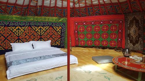 奥尔吉Ger ,Bulbul Jamak travel的一张位于多彩的墙壁和一张桌子的房间的床铺