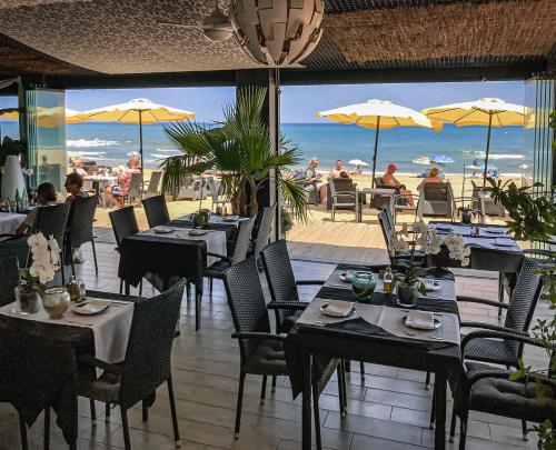 托雷维耶哈劳依兹海滩俱乐部酒店的一间设有桌椅的餐厅,享有海滩美景
