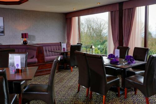 帕迪厄姆Burnley West Higher Trapp Hotel的用餐室配有桌椅和沙发